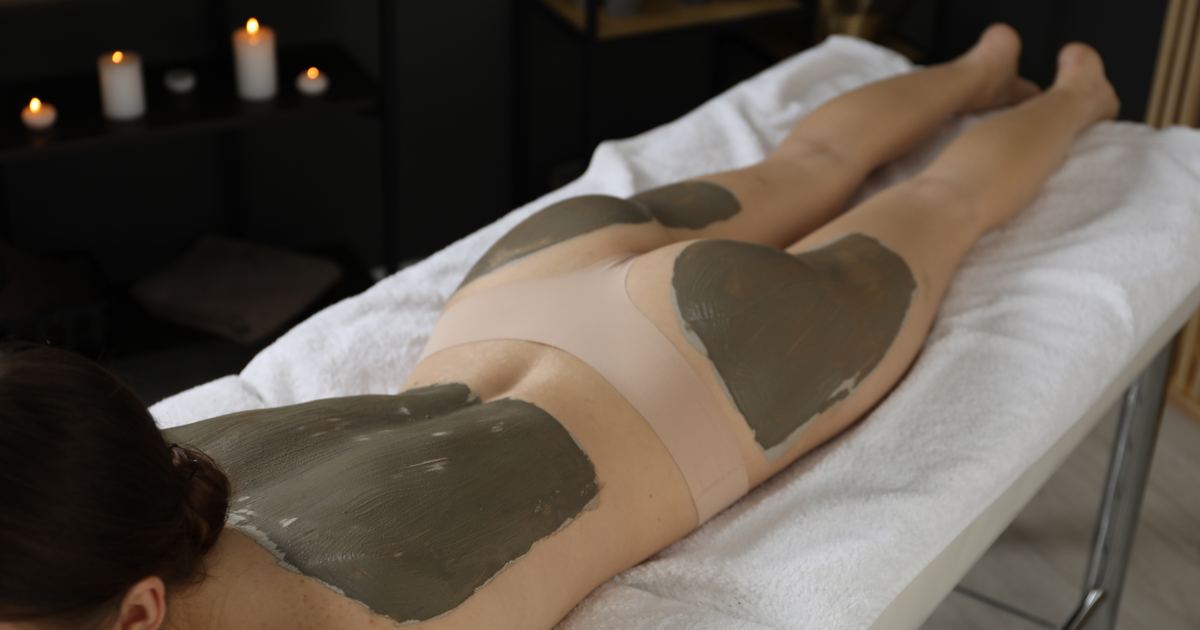 Moorpackung als Hausbesuch in München – Physiotherapie Köpple Warme Naturmoorpackung liegt auf dem Rücken einer Patientin während einer Wärmetherapie